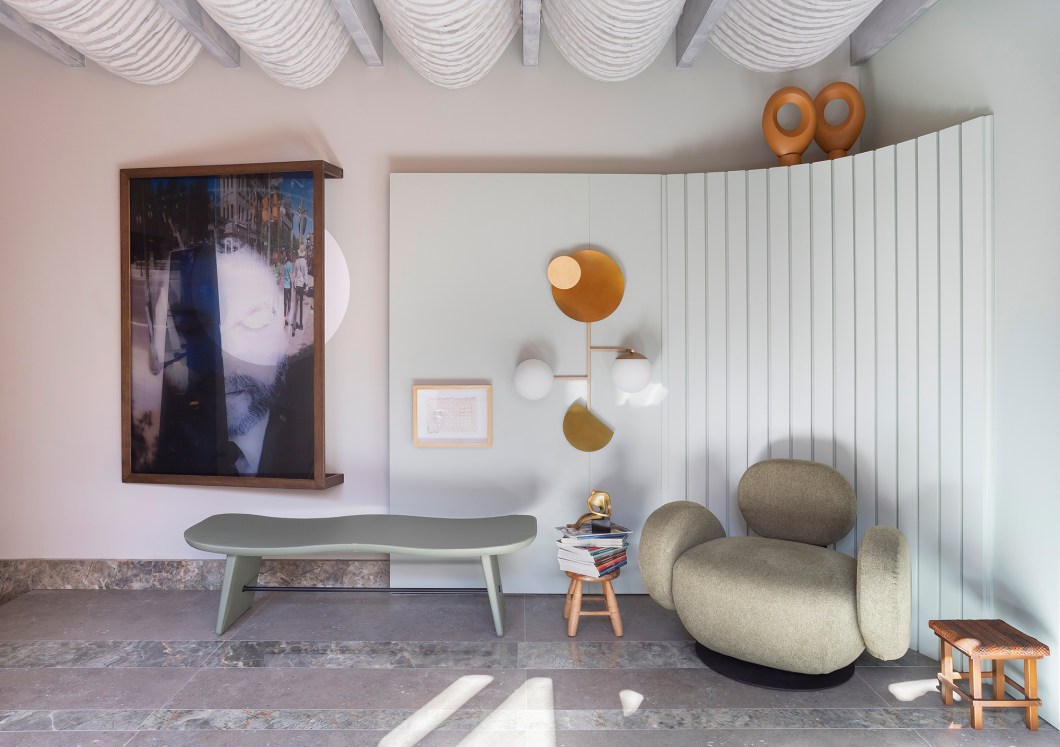 Mateus Passaglia e Nabila Feijó - eSPAço Abraço. A varanda contemporânea é uma reverência ao autocuidado e ao abraço. Um spa elegante dentro de casa, um espaço voltado para o bem-estar. A ideia é que o visitante respire devagar, e sinta toda a energia que existe ali. Sua experiência é direcionada por meio dos quatro elementos de conexão com a natureza: a terra, presente no paisagismo; o fogo, nas cores quentes que envolvem os jardins; a água, na estrutura do spa; e o ar, no movimento dos móbiles e dos tecidos e fios que vêm do teto. Nesse ambiente intimista, também estão em evidência o banco Mar, de Luan Del Salvio (Salva), o revestimento Gaya Green, que entra na paginação como um tapete incorporado à arquitetura, e as peças de arte popular sob a curadoria da Atelier na Rua/Casa do Brasil. “Em nossa varanda, hora você pode estar sozinho, abraçado por um céu azul, hora pode receber amigos para sentir-se abraçado com calor humano. Ela faz com que o visitante se sinta acolhido, que ele se sinta em casa”. Mateus Passaglia e Nabila Feijó - eSPAço Abraço. A varanda contemporânea é uma reverência ao autocuidado e ao abraço. Um spa elegante dentro de casa, um espaço voltado para o bem-estar. A ideia é que o visitante respire devagar, e sinta toda a energia que existe ali. Sua experiência é direcionada por meio dos quatro elementos de conexão com a natureza: a terra, presente no paisagismo; o fogo, nas cores quentes que envolvem os jardins; a água, na estrutura do spa; e o ar, no movimento dos móbiles e dos tecidos e fios que vêm do teto. Nesse ambiente intimista, também estão em evidência o banco Mar, de Luan Del Salvio (Salva), o revestimento Gaya Green, que entra na paginação como um tapete incorporado à arquitetura, e as peças de arte popular sob a curadoria da Atelier na Rua/Casa do Brasil. “Em nossa varanda, hora você pode estar sozinho, abraçado por um céu azul, hora pode receber amigos para sentir-se abraçado com calor humano. Ela faz com que o visitante se sinta acolhido, que ele se sinta em casa”.