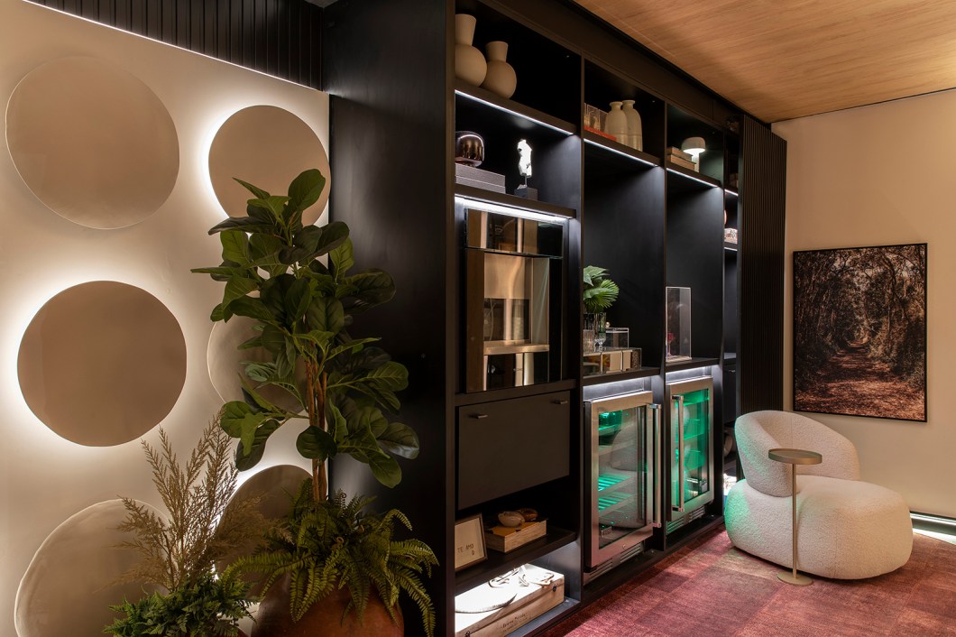 Studio AUHE Arquitetura - Caixa do Tempo. É possível fazer o tempo parar? Melissa Matara, Priscila Zanfrille e Thais Vilela mostram que sim nesse ambiente próprio para momentos de desconexão, essenciais à vida moderna. Como essa magia acontece? As arquitetas respondem com uma adega contemporânea, estilo que aparece principalmente em suas formas arredondadas. Elas ganham destaque no desenho do teto vinílico, uma releitura das caves tradicionais, e nas deliciosas poltronas de tecido bouclé. Em todos os detalhes, o cuidado para reforçar as sensações de tranquilidade, aconchego e bem-estar – do delicado mix de cores à iluminação intimista, da composição de tapetes e almofadas aos vasos que trazem a natureza para perto. “É um espaço para tornar a rotina mais leve, um convite ao repouso do corpo e da mente, proporcionando uma sensação de paz e despertando boas lembranças”. Studio AUHE Arquitetura - Caixa do Tempo. É possível fazer o tempo parar? Melissa Matara, Priscila Zanfrille e Thais Vilela mostram que sim nesse ambiente próprio para momentos de desconexão, essenciais à vida moderna. Como essa magia acontece? As arquitetas respondem com uma adega contemporânea, estilo que aparece principalmente em suas formas arredondadas. Elas ganham destaque no desenho do teto vinílico, uma releitura das caves tradicionais, e nas deliciosas poltronas de tecido bouclé. Em todos os detalhes, o cuidado para reforçar as sensações de tranquilidade, aconchego e bem-estar – do delicado mix de cores à iluminação intimista, da composição de tapetes e almofadas aos vasos que trazem a natureza para perto. “É um espaço para tornar a rotina mais leve, um convite ao repouso do corpo e da mente, proporcionando uma sensação de paz e despertando boas lembranças”.