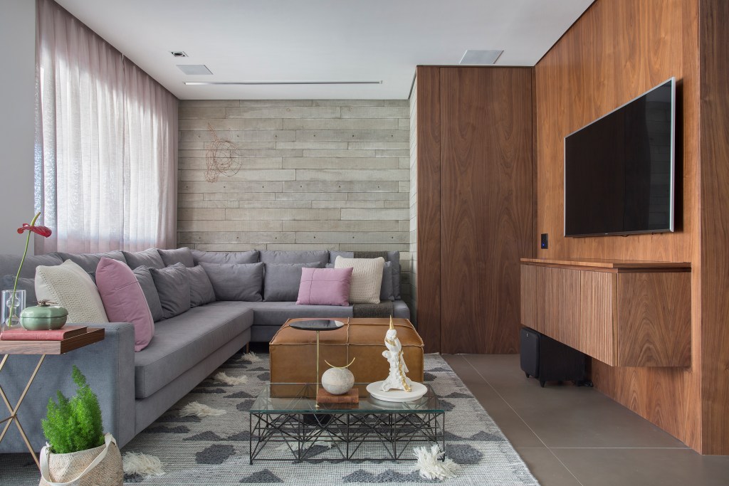 Apê de 95 m² ganha décor masculino para receber amigos e clientes. Projeto de Fabiano Ravaglio. Na foto sala com varanda e sofá em L. Porta camuflada na marcenaria.