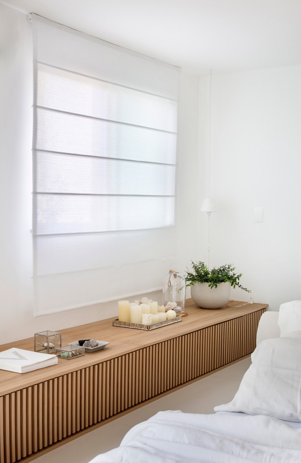 loft-40-m2-projeto-minimalista-une-branco-madeira-diego-raposo-manuela-simas-credito-mca (6) Loft de 40 m² ganha projeto minimalista que une branco e madeira. Projeto de Diego Raposo e Manuela Simas. Na foto, banco de marcenaria ripada no quarto.