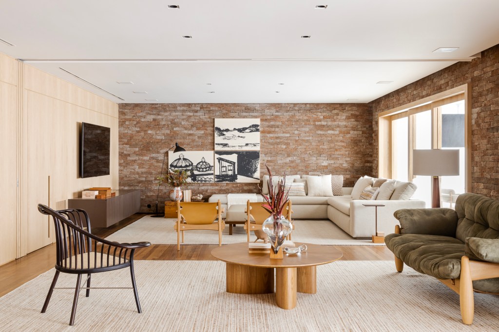 Apartamento Vila Nova Conceição Parede de tijolos e painéis de madeira trazem acolhimento ao apê de 310 m². Projeto Très Arquitetura. Na foto, sala de estar com parede de tijolinhos e madeira e varanda integrada.