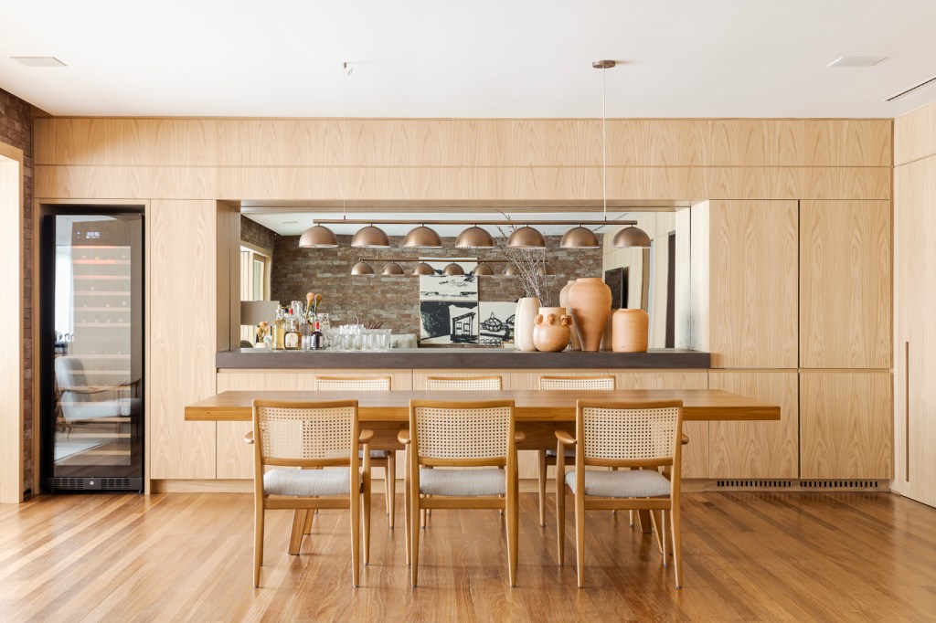Apartamento Vila Nova Conceição Parede de tijolos e painéis de madeira trazem acolhimento ao apê de 310 m². Projeto Très Arquitetura. Na foto, sala de estar com parede de tijolinhos e madeira e sala de jantar integrada.