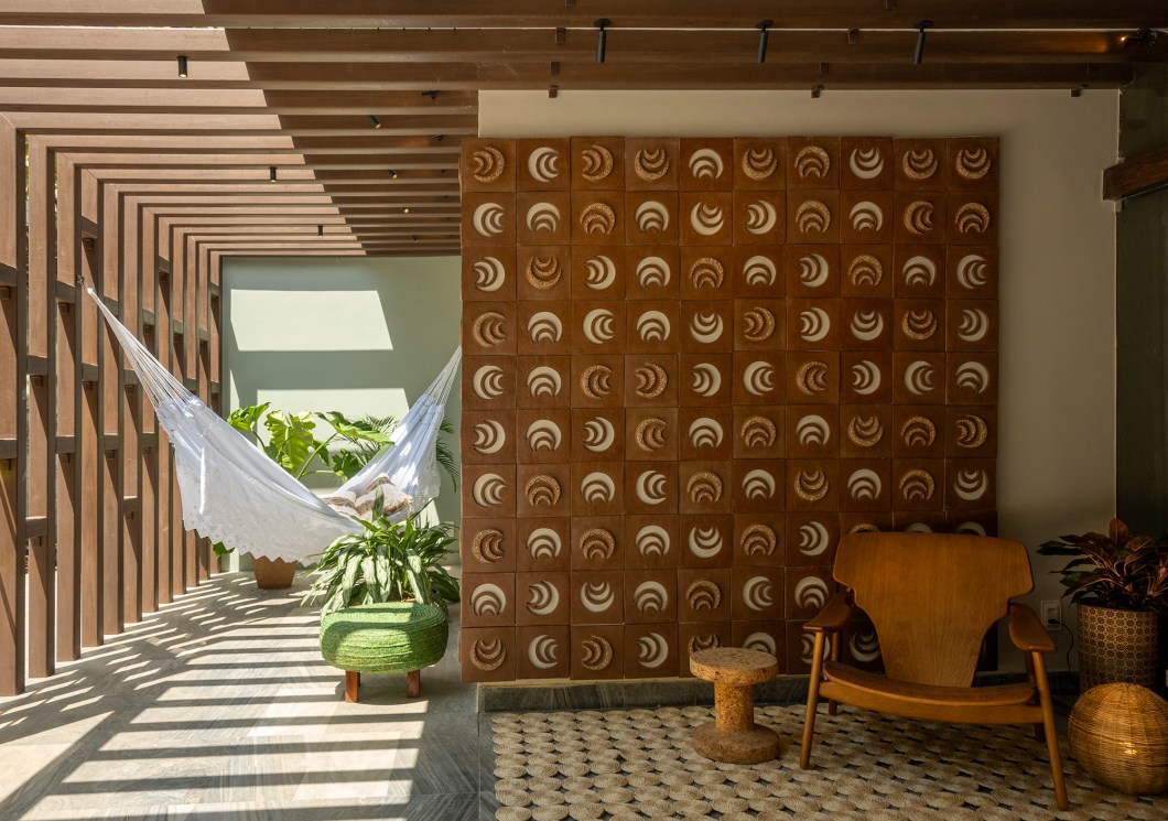 Curso de Arquitetura e Urbanismo - Varanda Unifor 50. <span>O espaço da Universidade de Fortaleza na CASACOR Ceará 2023 é uma varanda parcialmente coberta de 35 m², que comemora os 50 anos da instituição. O projeto incorpora elementos históricos da universidade, como a figura visionária de Edson Queiroz, representada por uma poltrona moderna e uma luminária, enquanto uma escultura e um painel cerâmico celebram sua trajetória. A parede oposta exibe a contribuição da universidade para a formação de profissionais e a arte local. O ambiente externo apresenta um pergolado com plantas cultivadas no campus da UNIFOR, destacando a área verde. Materiais naturais, como madeira e cerâmica, definem uma paleta terrosa em contraste com o verde e o mármore existente, criando uma atmosfera acolhedora.</span> Curso de Arquitetura e Urbanismo - Varanda Unifor 50. <span>O espaço da Universidade de Fortaleza na CASACOR Ceará 2023 é uma varanda parcialmente coberta de 35 m², que comemora os 50 anos da instituição. O projeto incorpora elementos históricos da universidade, como a figura visionária de Edson Queiroz, representada por uma poltrona moderna e uma luminária, enquanto uma escultura e um painel cerâmico celebram sua trajetória. A parede oposta exibe a contribuição da universidade para a formação de profissionais e a arte local. O ambiente externo apresenta um pergolado com plantas cultivadas no campus da UNIFOR, destacando a área verde. Materiais naturais, como madeira e cerâmica, definem uma paleta terrosa em contraste com o verde e o mármore existente, criando uma atmosfera acolhedora.</span>
