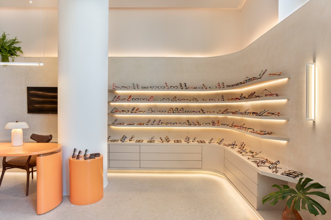 Nuit Arquitetura (Maria Celina Ferreira) - Gustavo Eyewear. O ambiente assinado pela arquiteta Maria Celina Ferreira traz uma atmosfera fluida e contemporânea para a loja de óculos Gus Eyewear. Apostando em paredes curvas, tons claros e texturas, o espaço acomoda com leveza, em sua marcenaria curvilínea, as coloridas peças feitas à mão. O mobiliário solto compõe o ambiente com cadeiras em tons sóbrios, como a madeira e couro, mesclando com as cores marcantes da mesa e poltrona, promovendo um contraste agradável e aconchegante. Nuit Arquitetura (Maria Celina Ferreira) - Gustavo Eyewear. O ambiente assinado pela arquiteta Maria Celina Ferreira traz uma atmosfera fluida e contemporânea para a loja de óculos Gus Eyewear. Apostando em paredes curvas, tons claros e texturas, o espaço acomoda com leveza, em sua marcenaria curvilínea, as coloridas peças feitas à mão. O mobiliário solto compõe o ambiente com cadeiras em tons sóbrios, como a madeira e couro, mesclando com as cores marcantes da mesa e poltrona, promovendo um contraste agradável e aconchegante.