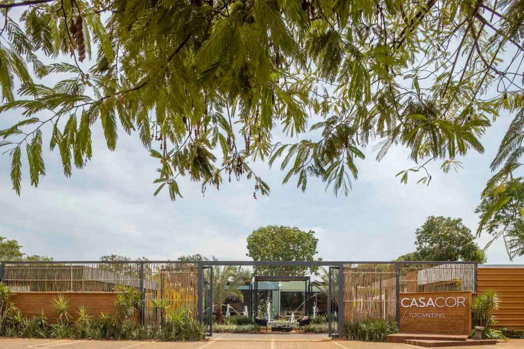 Renara Cardozo Arquitetura - Sentindo o Morar. A fachada da CASACOR Tocantins, pela primeira vez no formato original, tem assinatura da arquiteta Renara Cardozo, estreante na mostra. O projeto dá destaque ao regionalismo com a utilização de elementos naturais e sustentáveis, como o adobe, o bambu e as biribas. Em contraste com o ferro, traz esse conceito rústico moderno. Um grande portal, que ajuda no sombreamento, garante também permeabilidade visual pelo trabalho tramado manual feito por artesãos locais. As riquezas naturais que o cerrado nos oferece são destacadas pela vegetação escolhida pela estudante de paisagismo Kênia Borges. Paisagismo que abraça a área da CASACOR, dentro do Shopping Capim Dourado, e convida os visitantes a entrarem para percorrer os ambientes internos. Renara Cardozo Arquitetura - Sentindo o Morar. A fachada da CASACOR Tocantins, pela primeira vez no formato original, tem assinatura da arquiteta Renara Cardozo, estreante na mostra. O projeto dá destaque ao regionalismo com a utilização de elementos naturais e sustentáveis, como o adobe, o bambu e as biribas. Em contraste com o ferro, traz esse conceito rústico moderno. Um grande portal, que ajuda no sombreamento, garante também permeabilidade visual pelo trabalho tramado manual feito por artesãos locais. As riquezas naturais que o cerrado nos oferece são destacadas pela vegetação escolhida pela estudante de paisagismo Kênia Borges. Paisagismo que abraça a área da CASACOR, dentro do Shopping Capim Dourado, e convida os visitantes a entrarem para percorrer os ambientes internos.