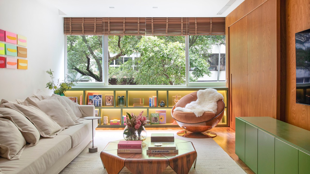 Apartamento em Ipanema é repleto de mobiliário de design brasileiro. Projeto de Bianca Da Hora. Na foto, sala de estar e jantar com parede de madeira e buffet verde.