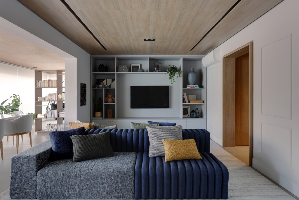 Apê moderno de 209 m² ganha toque francês com boiseries e molduras . Projeto de Barbara Dundes. Na foto, sala de estar com estante, sofá ilha e varanda integrada.