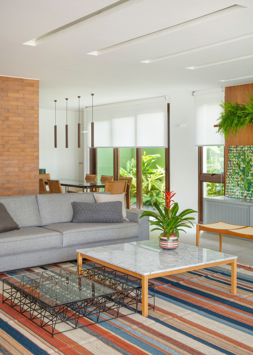 Casa de praia de 420 m² ganha estilo urbano e loft na garagem. Projeto Studio 021 Arquitetura. Na foto, sala de estar com sofá cinza e tapete listrado.