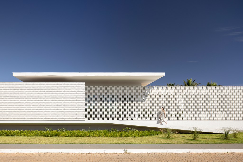 Tijolos brancos e vazados compõem fachada de casa de 600 m² em Brasília. Projeto de Bloco Arquitetos. Na foto, fachada da casa com muro de tijolos vazados.