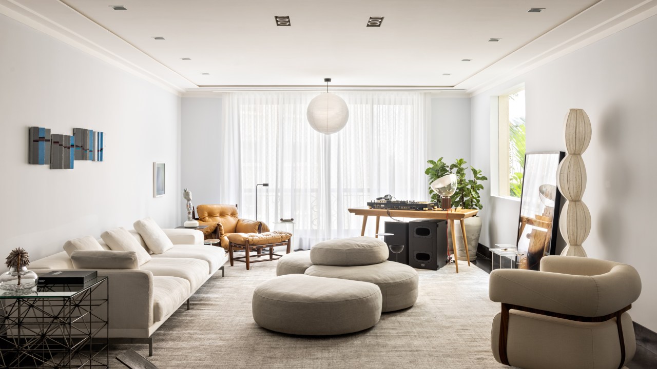 Apartamento de 550 m² ganha espaço para cabine de DJ no living. Projeto de Navarro Arquitetura. Na foto, living com quadro, cabine de dj, sofa ilha e quadros.