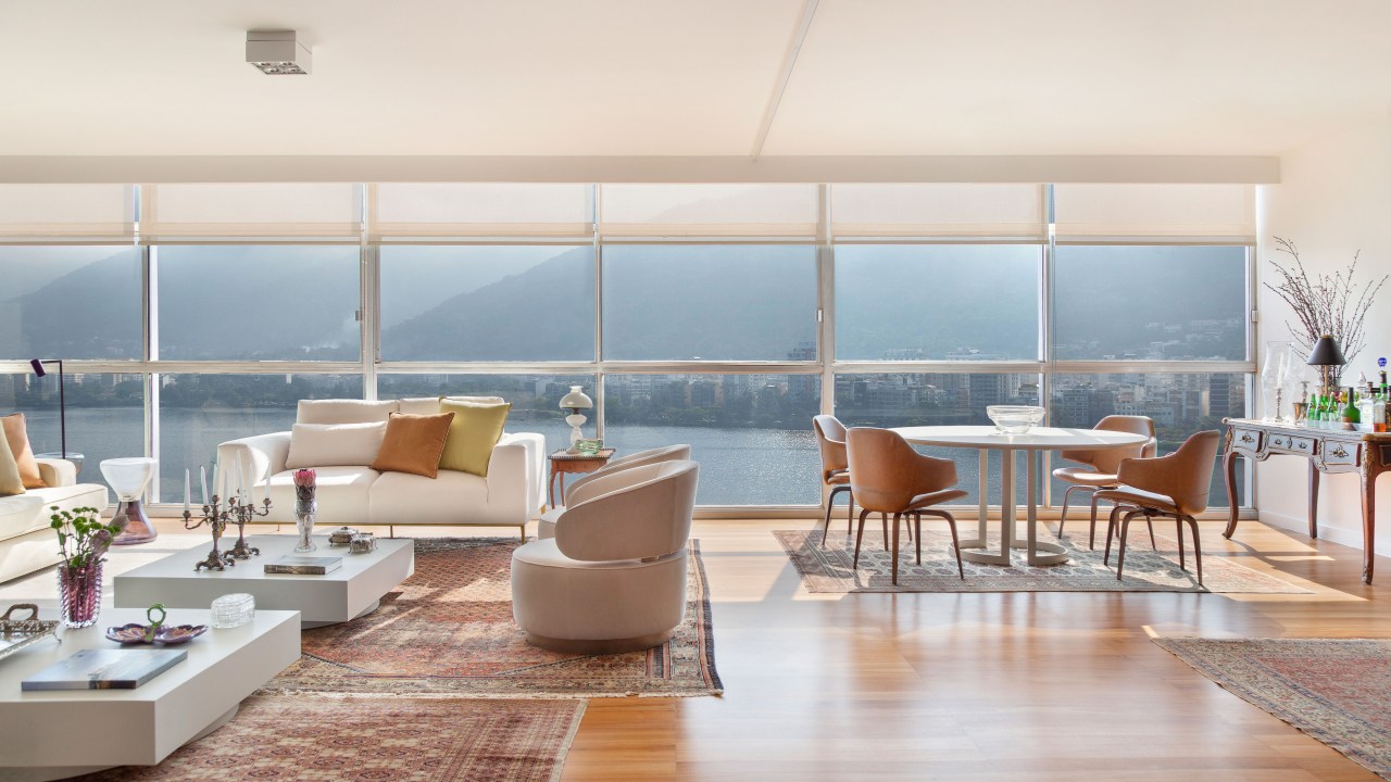 Apê de 450 m² com vista para Lagoa mescla peças novas e de acervo no décor. Projeto de Ricardo Melo e Rodrigo Passos. Na foto, sala estar com sofá branco, marcenaria e vista para a Lagoa.