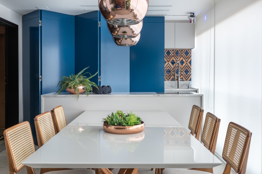 Painel retrátil esconde a churrasqueira neste apê descolado de 120 m². Projeto de Beatriz Quinelato. Na foto, varanda gourmet com painel azul que esconde a churrasqueira.