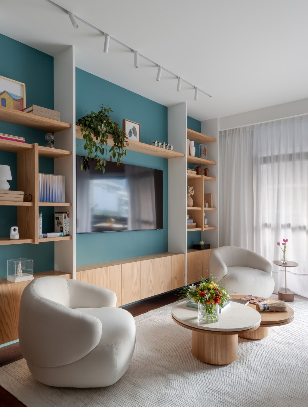 Apartamento de 140 m² ganha charme com paredes azuis e verdes. Projeto de Maia Romeiro Arquitetura. Na foto, sala de estar com parede azul e estante vazada.