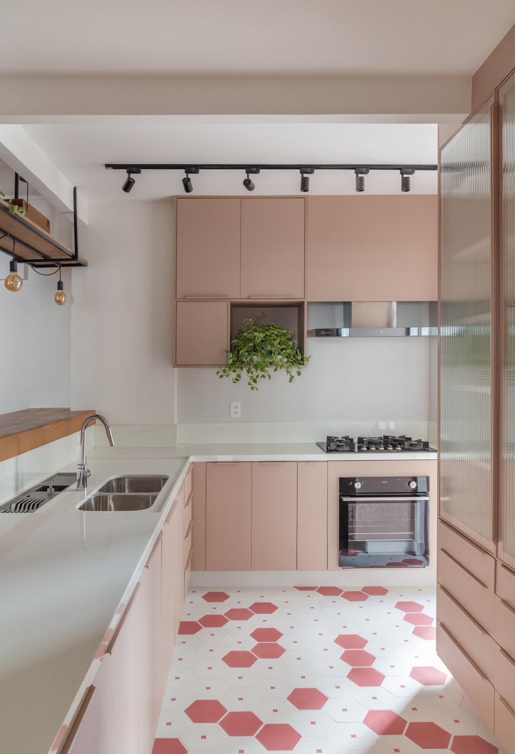 Apê de 145 m² ganha charme com tijolinhos, ladrilho hidráulico e patchwork. Na foto, cozinha com marcenaria rosa e piso hexagonal.