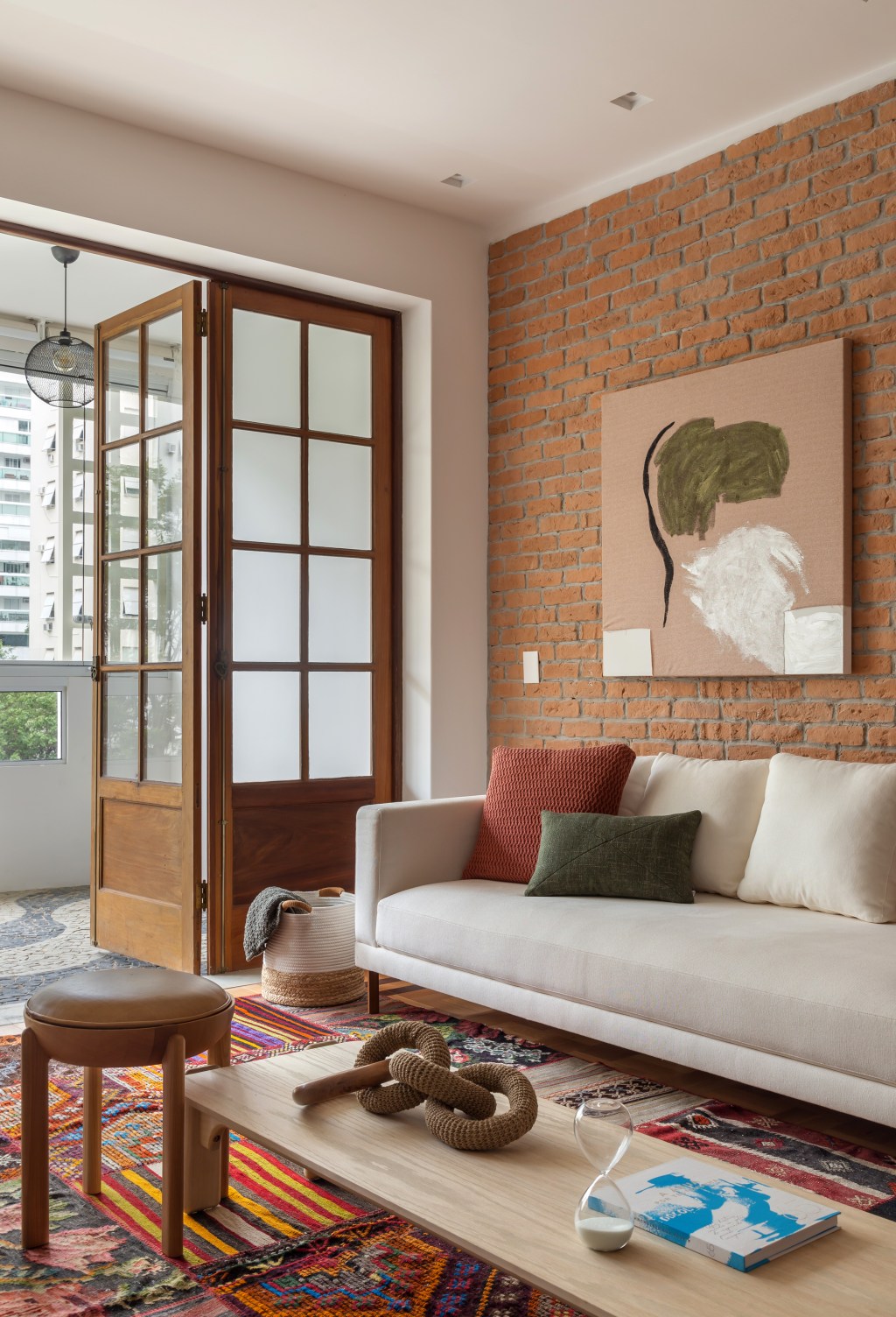ape-145-m2-charme-tijolinhos-ladrilho-hidraulico-patchwork-casa-studio-ninho-credito-luiza-schreier (5) Apê de 145 m² ganha charme com tijolinhos, ladrilho hidráulico e patchwork. Na foto, sala com parede de tijolinhos, tapete de patchwork e aparador.