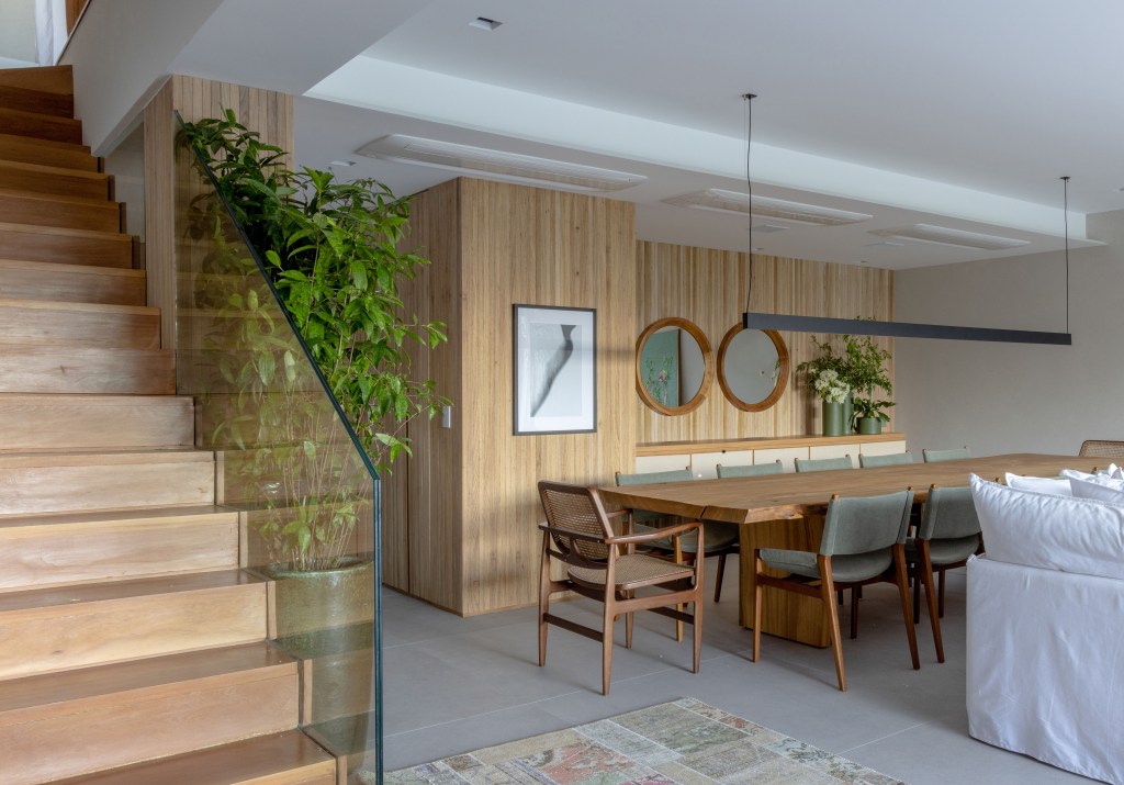 Casa é modernizada e ganha projeto de 845 m² distribuídos em cinco andares. Projeto Escala Arquitetura. Na foto. sala de jantar com escada e paredes amadeiradas.