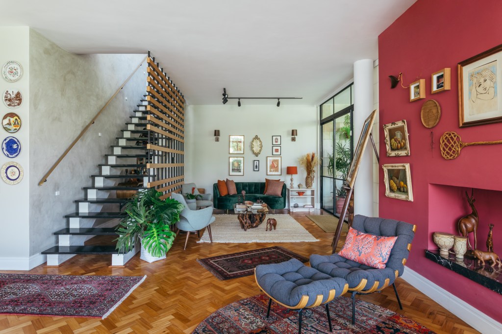 Casa no Parque Guinle une peças de família e décor contemporâneo. Projeto de Ana Cano. Na foto, sala com brise na escada, adega e quadros. Lareira e parede rosa.