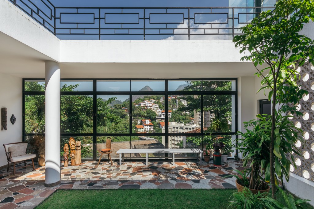 Casa no Parque Guinle une peças de família e décor contemporâneo. Projeto de Ana Cano. Na foto, varanda com piso de pedras, vista para o cristo e banco.