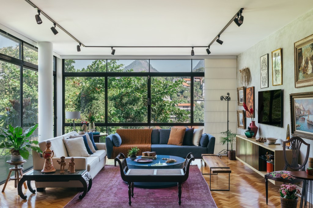 Casa no Parque Guinle une peças de família e décor contemporâneo. Projeto de Ana Cano. Na foto, sala com vista para o jardim e pilar. Tv e sofá azul.