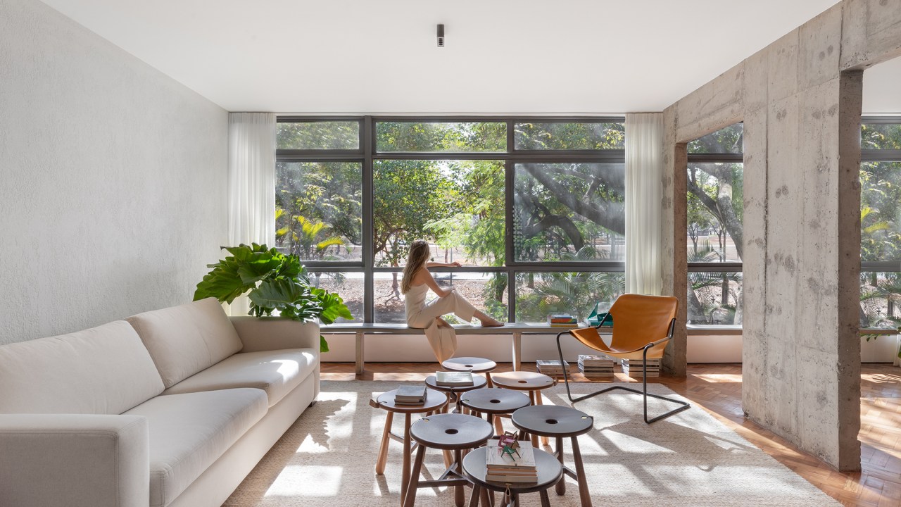 Apê brutalista em Brasília mescla cobogó, ladrilho e concreto no décor. Projeto de Maria Araujo Arquitetura, Na foto, sala com parede de concreto e vista para as árvores.