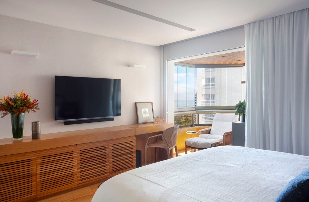 materiais-nobres-paleta-atemporal-marcam-apartamento-280-m2-studio-0210-credito-mca-estudio (8) Materiais nobres e paleta atemporal marcam este apartamento de 280 m². Projeto de Studio 021. Na foto, quarto de casal com varanda, tv e aparador ripado.