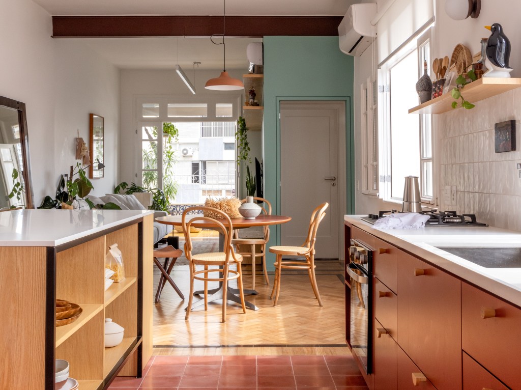 Apê de 90 m² ganha cara de casa com revestimentos charmosos e cores. Projeto Ana Neri. Na foto, cozinha com marcenaria terrosa e sala de jantar com mesa redonda.