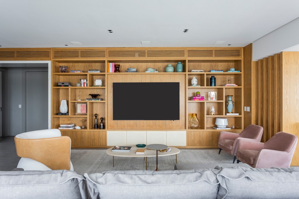 contemporaneidade-integracao-tons-neutros-apartamento-311-m2-bzp-arquitetura-credito-thiago-travesso (12) Contemporaneidade, integração e tons neutros marcam apartamento de 311 m². Projeto BZP Arquitetura. Na foto, sala de estar com estante embutida e poltronas rosas.