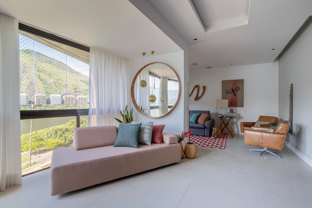 Cores vivas marcam décor deste apartamento de 300 m² com pé-direito duplo. Projeto de Ana Cano. Na foto, sala com espehos. sofás e vista para a natureza.
