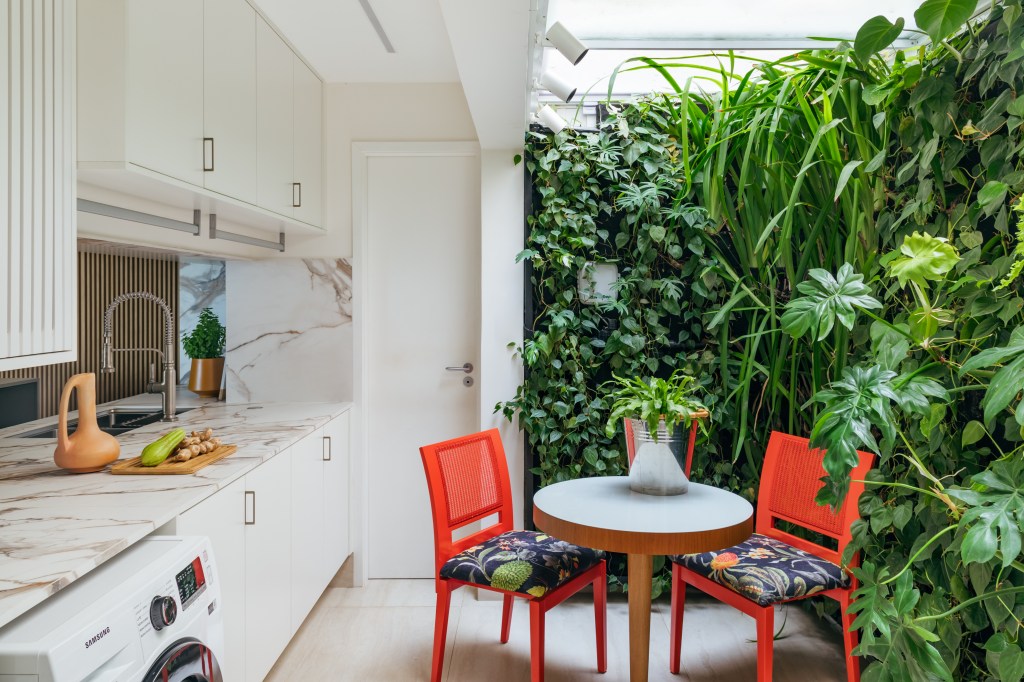 Apê de 350 m² tem vista para o mar, sauna e canto especial para charutos. Projeto de Vivian Reimers. Na foto, espaço gourmet com parede verde e cadeiras vermelhas.