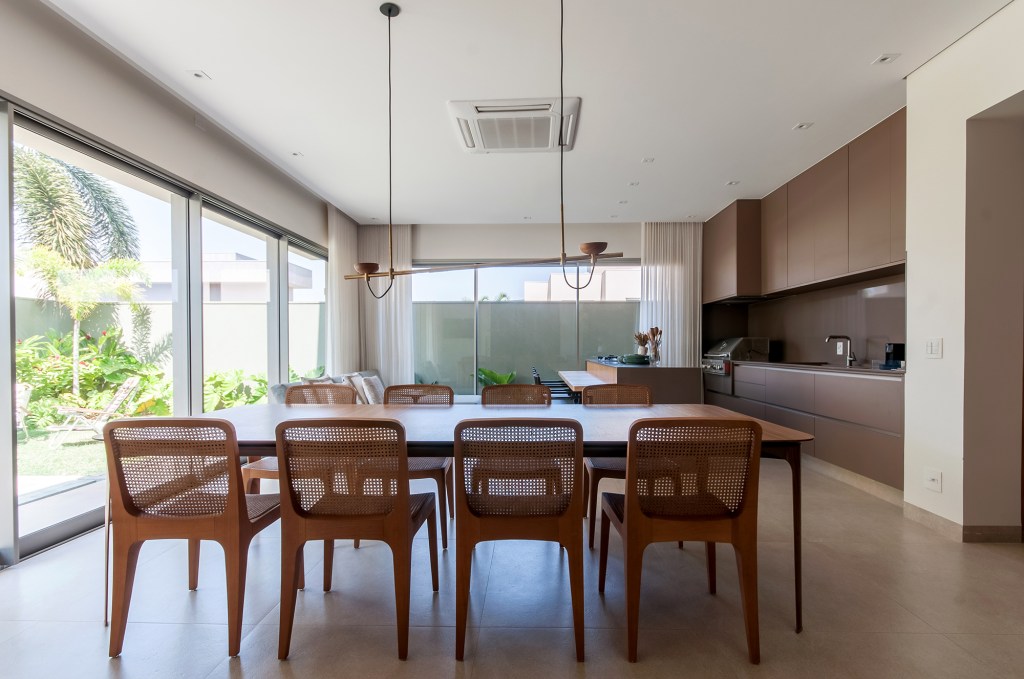 construida-do-zero-casa-ambientes-integrados-design-nacional-paiva-passarini-credito-xavier-neto (10) Construída do zero, casa une ambientes integrados e design nacional. Projeto de Paiva e Passarini Arquitetura. Na foto, sala de jantar com cadeira de palhinha e cozinha integrada.
