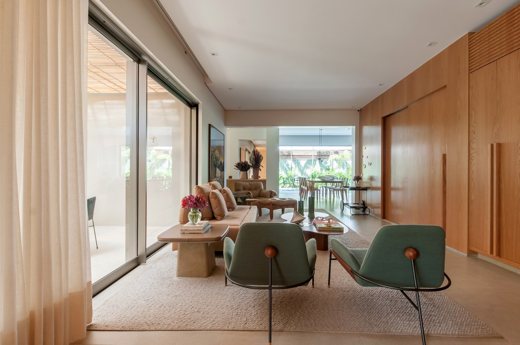 construida-do-zero-casa-ambientes-integrados-design-nacional-paiva-passarini-credito-xavier-neto (3) Construída do zero, casa une ambientes integrados e design nacional. Projeto de Paiva e Passarini Arquitetura. Na foto, sala de estar com painel de madeira e quadros.