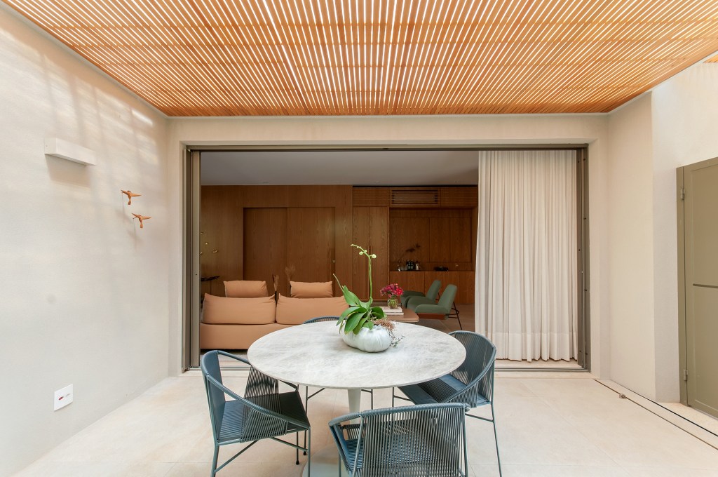 construida-do-zero-casa-ambientes-integrados-design-nacional-paiva-passarini-credito-xavier-neto (8) Construída do zero, casa une ambientes integrados e design nacional. Projeto de Paiva e Passarini Arquitetura. Na foto, varanda com teto ripado e mesa.