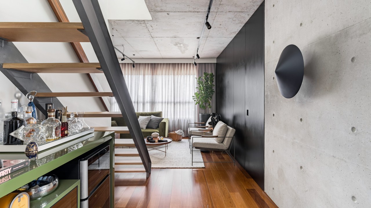 Gabriela Prado assina apê industrial de 140 m² com jardim de cactos. Na foto, sala com parede preta e escada vazada.