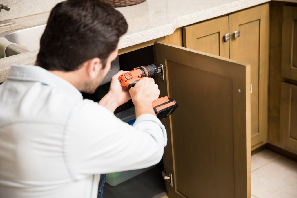 Handyman fixing a kitchen cabinet Instalando móvel