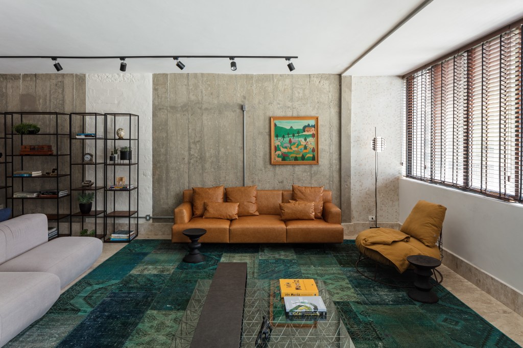 José Navarro assina apartamento de 210 m² no Conjunto Nacional, em SP. Na foto, sala de estar com sofá de couro, tapete e quadros.
