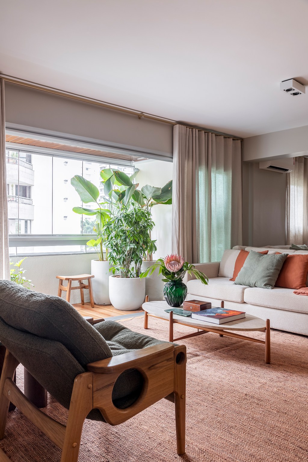 Paola Ribeiro assina apartamento de 196 m² com alma carioca em SP. Projeto de Paola Ribeiro, Na foto, sala de estar com poltronas, varanda e sofá ilha.