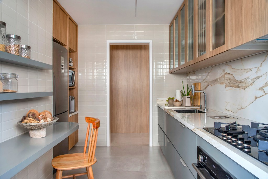 Sem quebra-quebra, apê de 92 m² ganha projeto afetivo e com biofilia. Projeto de Fabiano Ravaglia. Na foto, cozinha com marcenaria cinza e armário com vidro canelado.