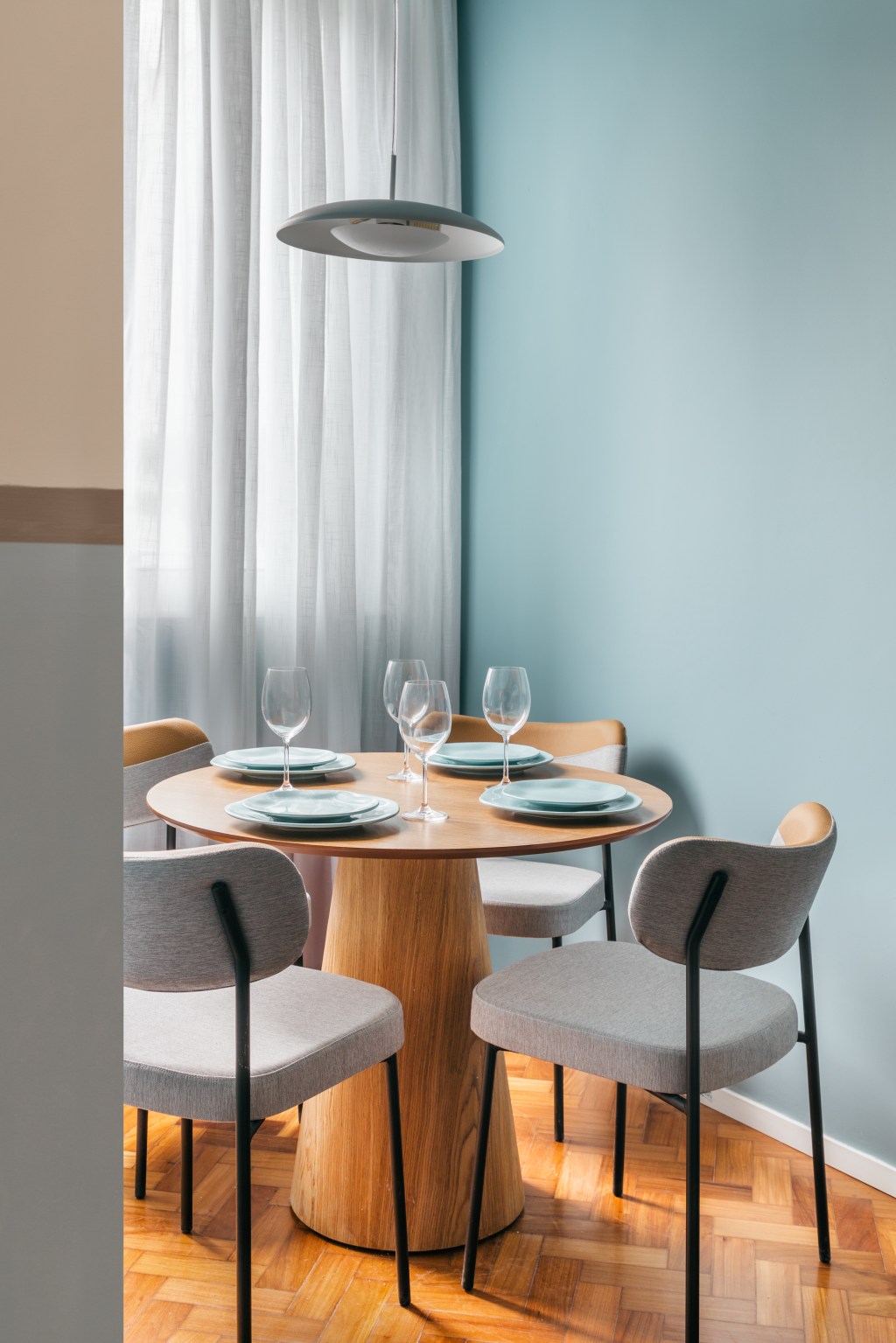 Apê de 25 m² ganha décor praiana com parede de cerâmica azul. Projeto de Rodolfo Consoli. Na foto, sala de jantar com mesa redonda de madeira.