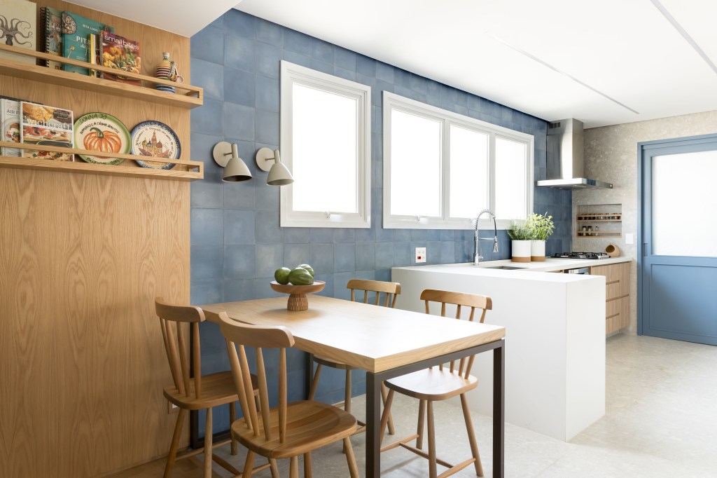 Apto Brooklin Novo Apê eclético: minimalismo, shabby chic e industrial se mesclam em 180 m². Projeto Studio Lak. Na foto, cozinha com parede azul, copa e mesa de refeições.