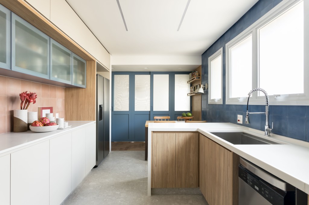 Apê eclético: minimalismo, shabby chic e industrial se mesclam em 180 m². Projeto Studio Lak. Na foto, cozinha com parede azul, copa e mesa de refeições.