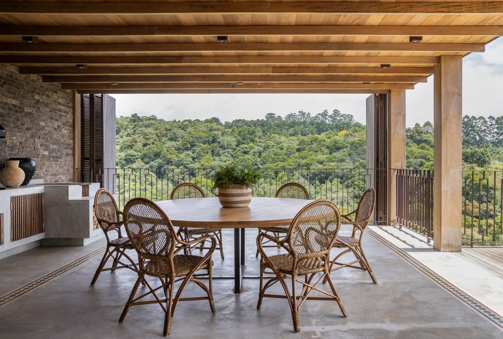 casa-sustentavel-ntegrada-natureza-frente-campo-golfe-in-house-credito-evelyn-muller (13) Casa sustentável e integrada à natureza fica em frente ao campo de golfe. Projeto de In House Arquitetura. Na foto, varanda com mesa de jantar e forno a lenha.