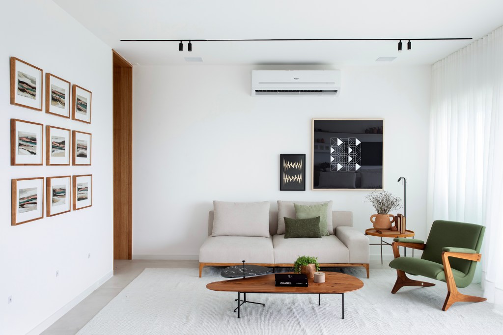 De frente para o mar, um apartamento ideal para curtir a aposentadoria. Projeto de Rafael Ramos. Na foto, sala com sofá, poltrona e quadros.