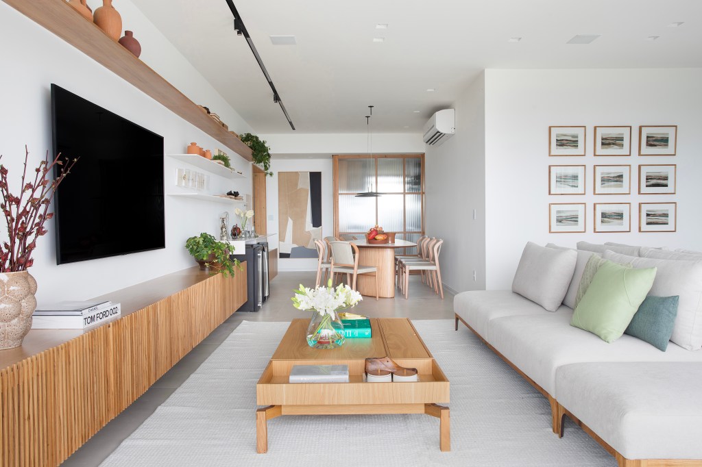 De frente para o mar, um apartamento ideal para curtir a aposentadoria. Projeto de Rafael Ramos. Na foto, sala com sofá, poltrona e quadros. Tv e jantar,