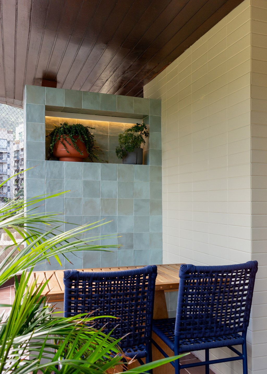 madeira-protagonista-apartamento-117-m2-gavea-mariana-monnerat-credito-lilia-mendel (19) A madeira é a protagonista deste apartamento de 117 m² na Gávea. Projeto de Mariana Monnerat, Na foto, varanda com cadeira azul e vasos.