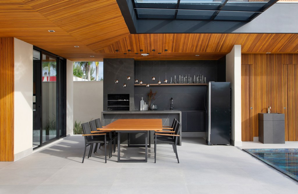 paineis-madeira-estilo-minimalista-tom-casa-780-m2-hannah-cabral-monique-pampolha-credito-denilson-machado (1) Painéis de madeira e estilo minimalista dão o tom desta casa de 780 m². Projeto de Hannah Cabral e Monique Pampolha. Na foto, varanda gourmet com piscina e churrasqueira,