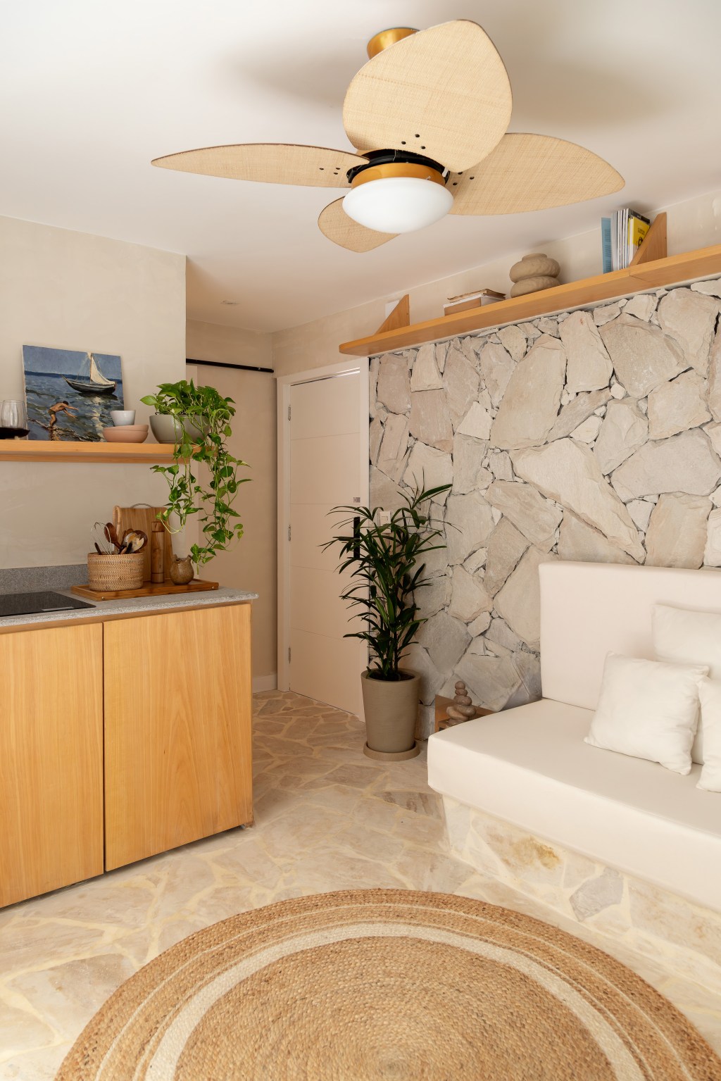 Apartamento térreo em Ipanema onde mora a arquiteta TAINÁ BINATO, do escritório CASA TAUARI ARQUITETURA _ foto 2.2 Reforma transforma imóvel de 45 m² em refúgio tropical. Projeto de Tauari Arquitetura. Na foto, sala com parede de pedra e sofá de alvenaria.