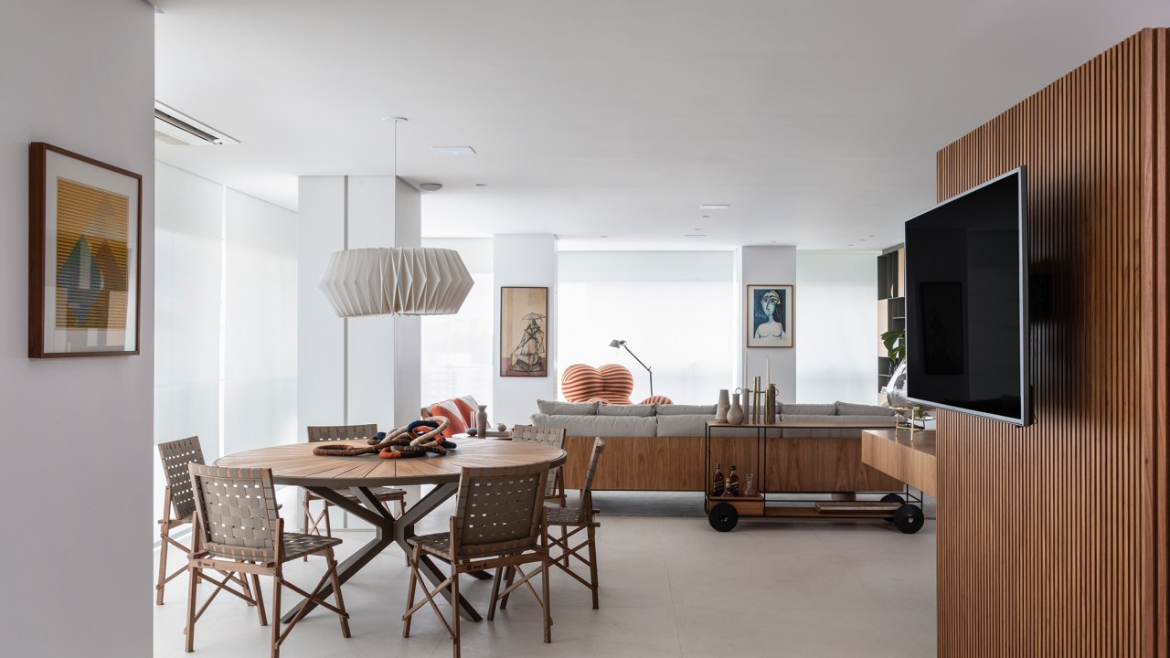 Acervo de arte do morador norteia projeto assinado por Sala2 Arquitetura. Na foto, sala jantar e estar integradas. Mesa redonda e pendente.