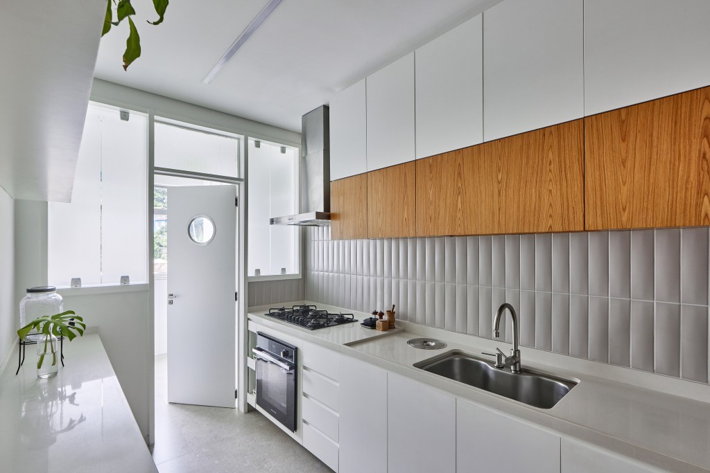 apartamento-98-m2-decor-contemporaneo-toques-brutalismo-hugo-rapizo-credito-rafael-salim (16) Apartamento de 98 m² ganha décor contemporâneo, mas com toques de brutalismo. Projeto de Hugo Rapizo. Na foto, cozinha corredor com marcenaria branca.