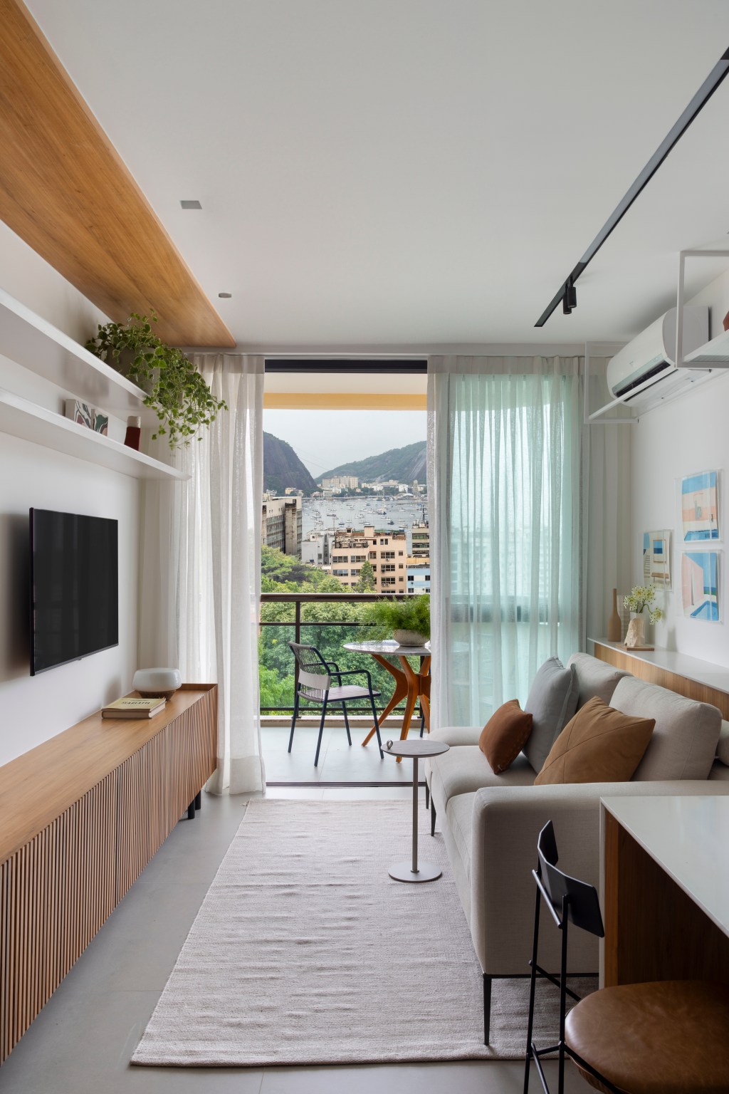branco-madeira-decor-cozy-apartamento-70-m2-rafael-ramos-credito-juliano-colodeti (8) Branco e madeira criam décor cozy em apartamento de 70 m². Projeto de Rafael Ramos. Na foto, sala de tv com aparador ripado e bancos escondidos.