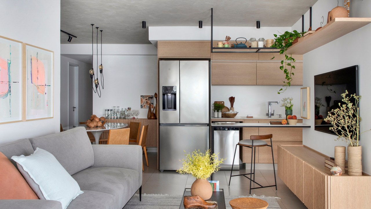 Reforma em apê de 105 m² cria lar aconchegante para mãe e filha. Projeto de Rafael Ramos. Na foto, sala com cozinha integrada e marcenaria ripada.